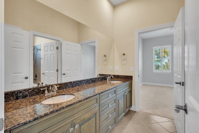 full bath featuring double vanity, a sink, baseboards, and tile patterned floors