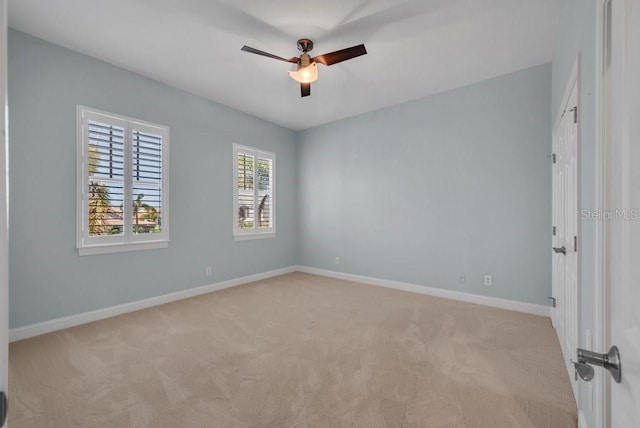 empty room featuring light carpet, ceiling fan, and baseboards