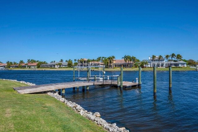 view of dock with a water view and a yard