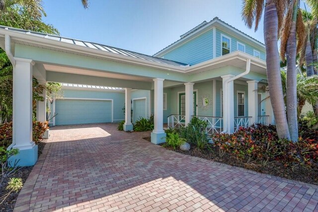 view of front of home featuring metal roof, a porch, an attached garage, decorative driveway, and a standing seam roof