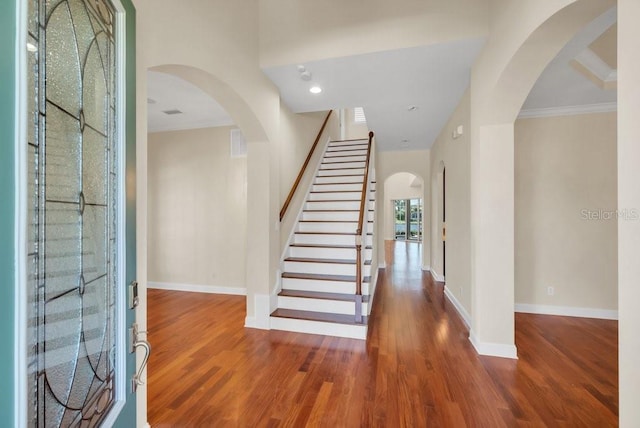 entryway featuring arched walkways, wood finished floors, visible vents, baseboards, and stairway