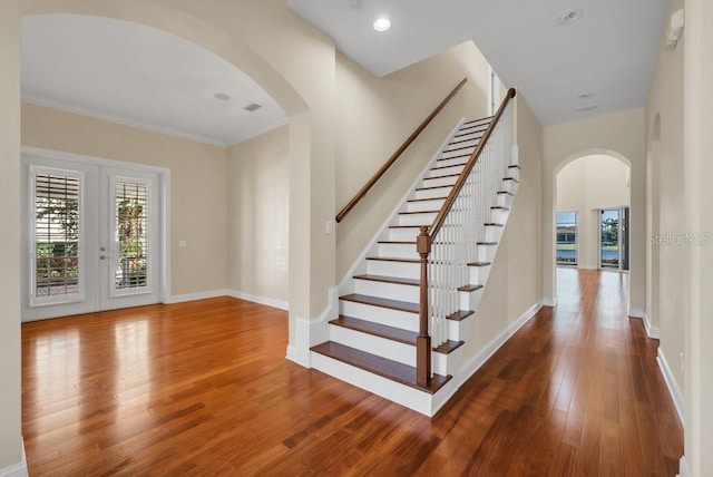 interior space with arched walkways, wood-type flooring, baseboards, and plenty of natural light