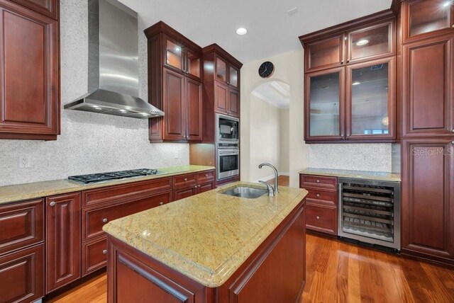 kitchen with wine cooler, gas cooktop, oven, a sink, and wall chimney range hood