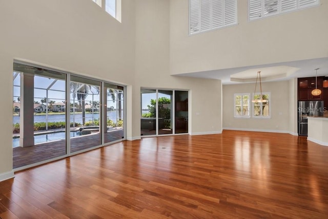 unfurnished living room with a water view, baseboards, and wood finished floors