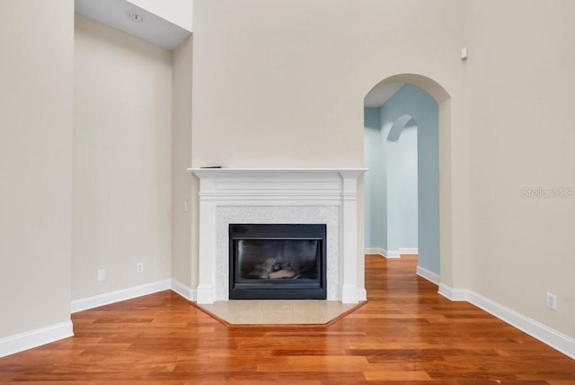 unfurnished living room with baseboards, wood finished floors, and a tile fireplace