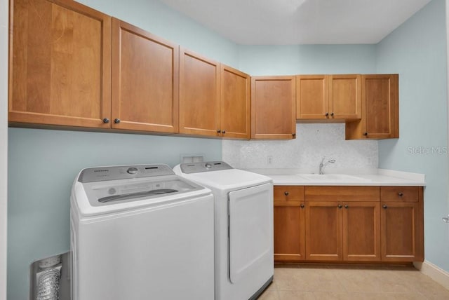 clothes washing area with cabinet space, light tile patterned floors, separate washer and dryer, and a sink