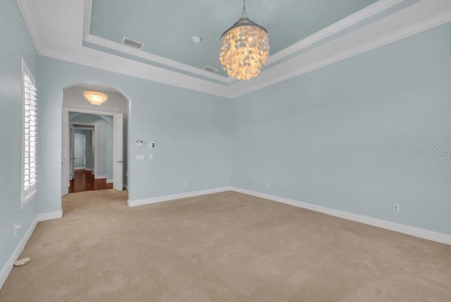 unfurnished room with arched walkways, visible vents, baseboards, ornamental molding, and a raised ceiling