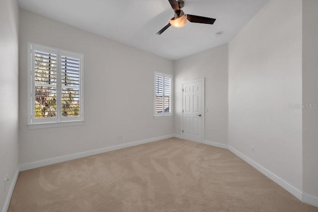 spare room featuring light carpet, ceiling fan, and baseboards