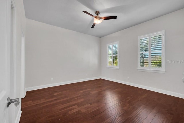 empty room featuring dark wood-style flooring, a ceiling fan, and baseboards