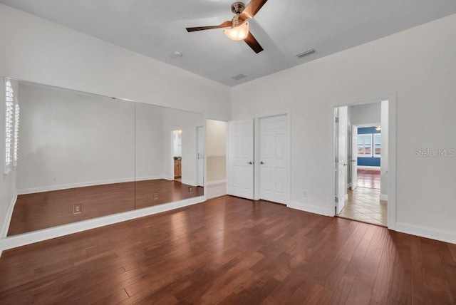 unfurnished bedroom featuring a ceiling fan, visible vents, baseboards, and wood finished floors