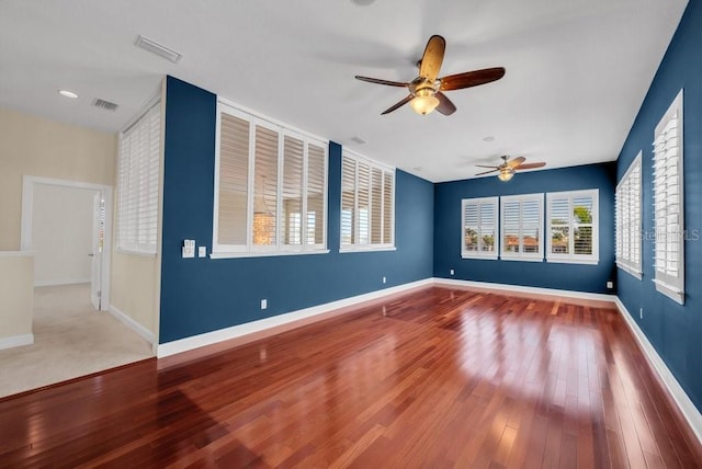 unfurnished room with baseboards, visible vents, and wood finished floors