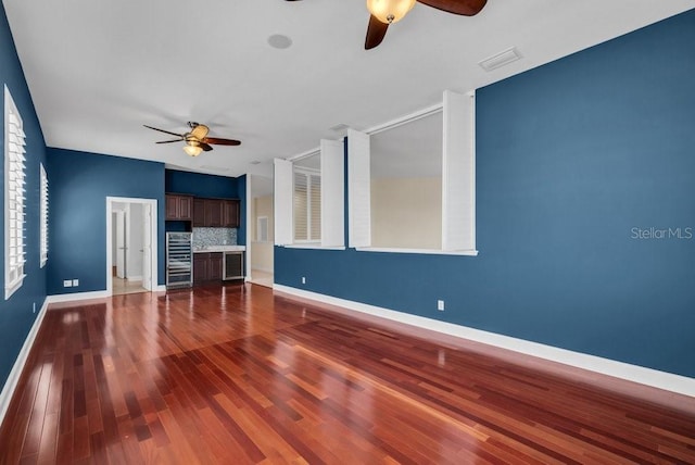 interior space featuring baseboards, visible vents, a ceiling fan, wine cooler, and wood finished floors