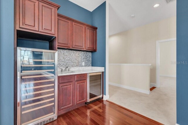 kitchen featuring beverage cooler, dark wood-type flooring, backsplash, and baseboards