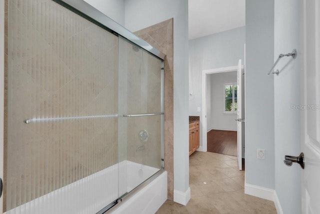 full bathroom with tile patterned floors, baseboards, combined bath / shower with glass door, and vanity