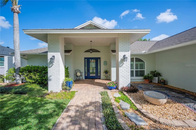 doorway to property with a shingled roof and stucco siding