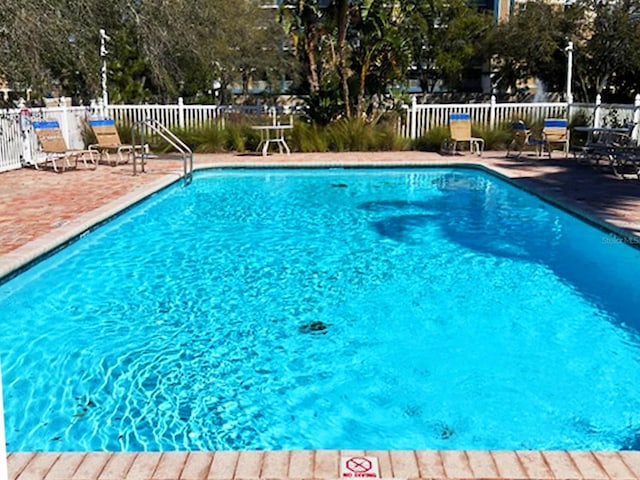 community pool with a patio and fence