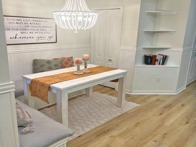 dining area featuring wood finished floors, a chandelier, and wainscoting