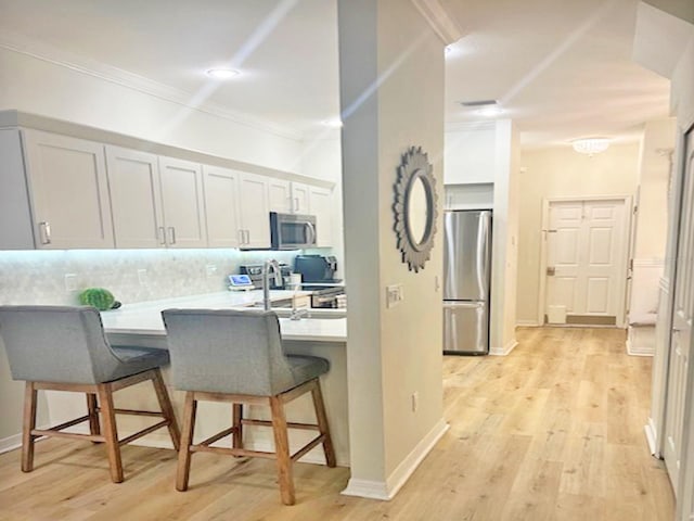 kitchen featuring a sink, backsplash, stainless steel appliances, a peninsula, and a breakfast bar area