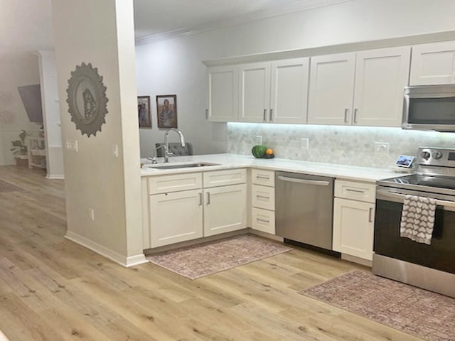 kitchen with a sink, stainless steel appliances, crown molding, and light countertops