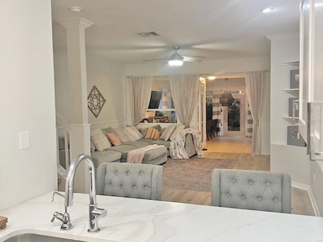 living area with visible vents, ceiling fan, and decorative columns