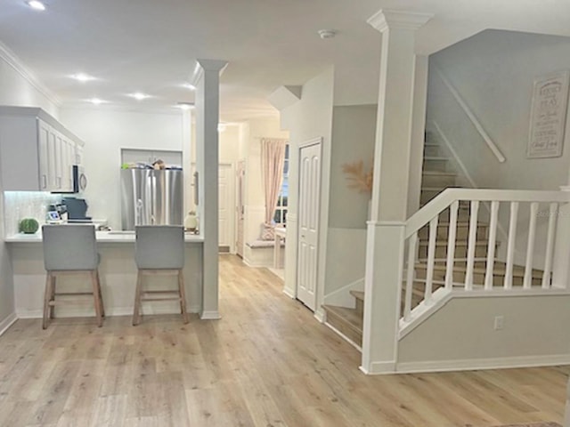 kitchen with light wood-style floors, a breakfast bar, a peninsula, and freestanding refrigerator