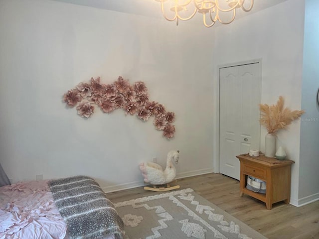 bedroom featuring wood finished floors, baseboards, and a chandelier