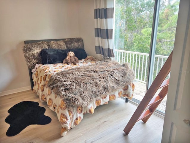 bedroom with access to exterior, wood finished floors, and baseboards