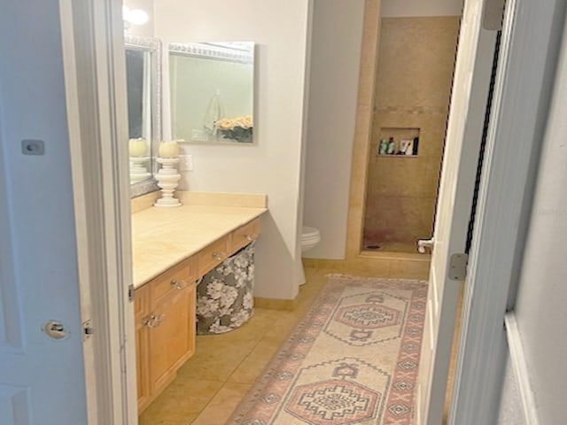 full bath featuring toilet, a stall shower, tile patterned flooring, baseboards, and vanity