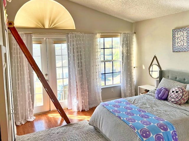 bedroom featuring french doors, a textured ceiling, wood finished floors, and vaulted ceiling