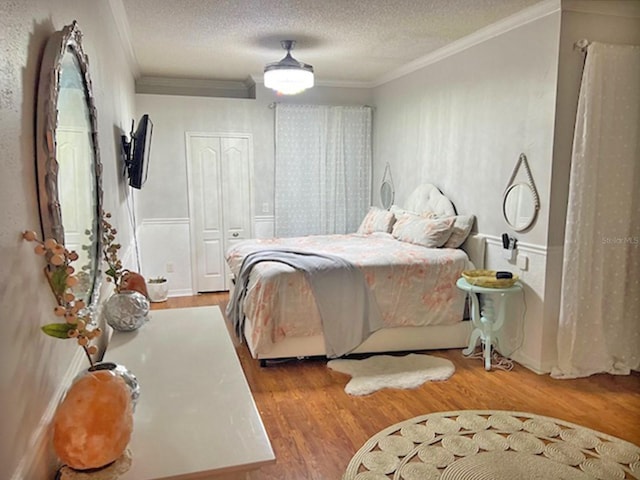 bedroom featuring ceiling fan, a textured ceiling, wood finished floors, and crown molding