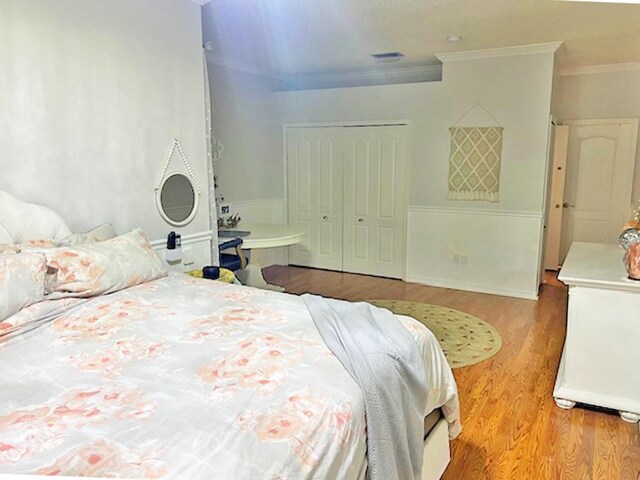 bedroom featuring crown molding, wood finished floors, and a closet