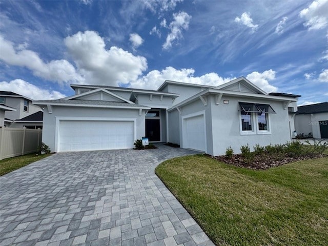 ranch-style house featuring a garage, decorative driveway, a front lawn, and stucco siding