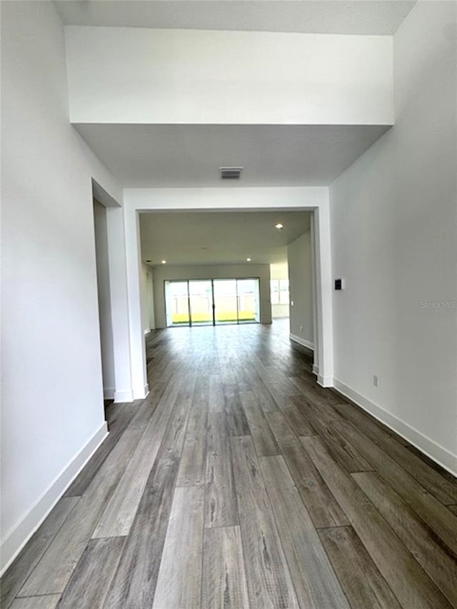 unfurnished room featuring dark wood finished floors, visible vents, and baseboards