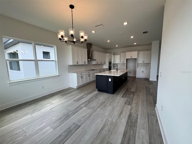 kitchen featuring wall chimney exhaust hood, tasteful backsplash, a sink, and visible vents