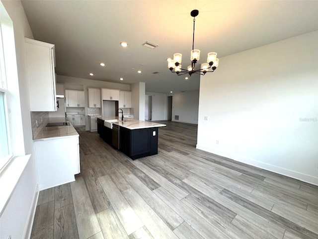 kitchen with white cabinets, open floor plan, an inviting chandelier, light countertops, and light wood-style floors