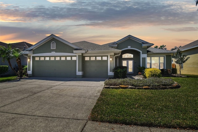 view of front of home featuring a garage, a lawn, concrete driveway, and stucco siding