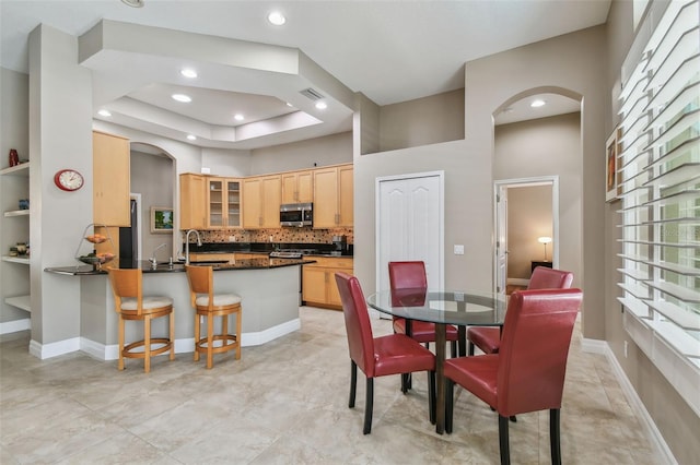 dining space with visible vents, recessed lighting, arched walkways, a high ceiling, and baseboards