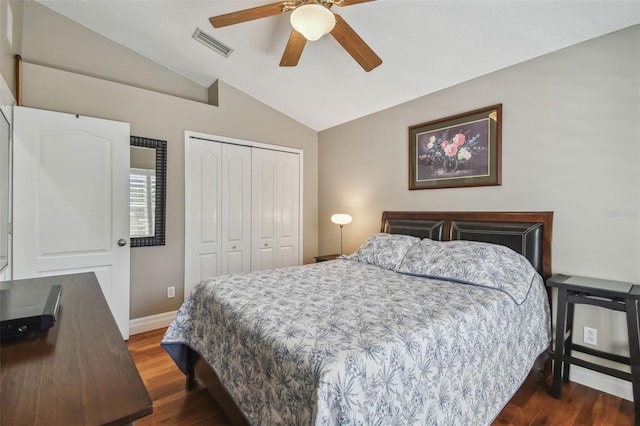 bedroom featuring visible vents, lofted ceiling, a closet, baseboards, and dark wood-style flooring