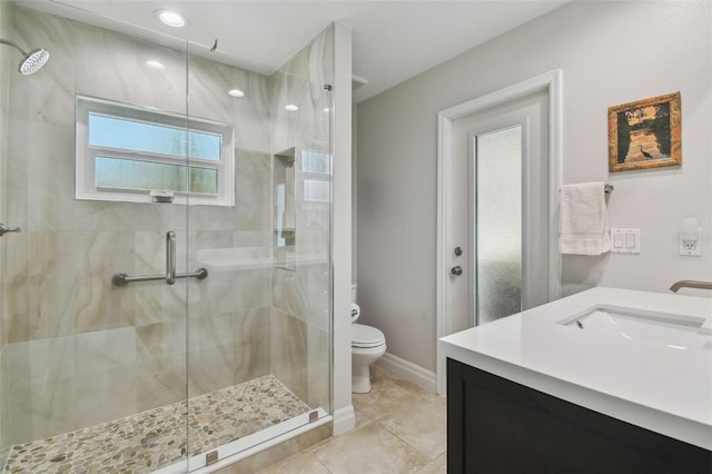 bathroom featuring tile patterned flooring, baseboards, toilet, a stall shower, and a sink