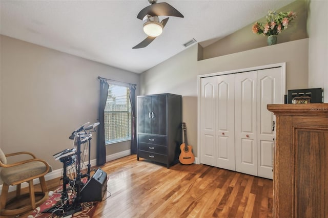 living area with visible vents, wood finished floors, baseboards, ceiling fan, and vaulted ceiling