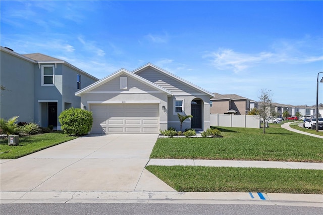 view of front facade with a garage, driveway, fence, a front yard, and stucco siding