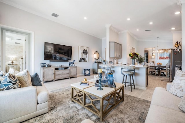 living room featuring ornamental molding, recessed lighting, visible vents, and light wood finished floors