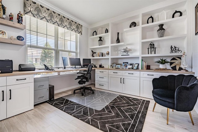 office featuring light wood-type flooring, built in study area, and crown molding