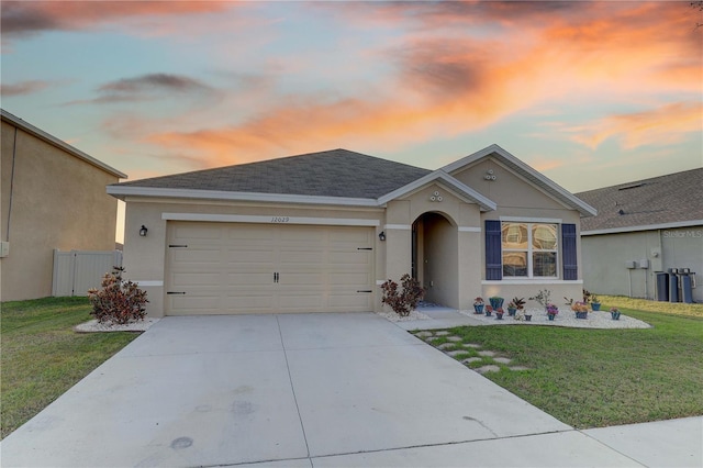 ranch-style home featuring driveway, stucco siding, roof with shingles, an attached garage, and a front yard