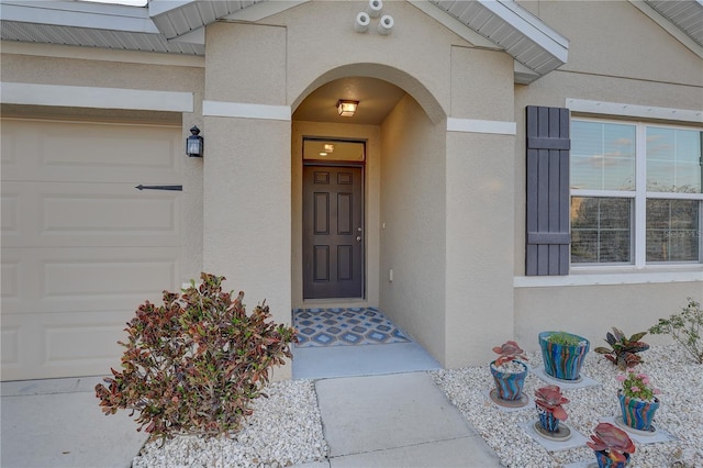 entrance to property with an attached garage and stucco siding