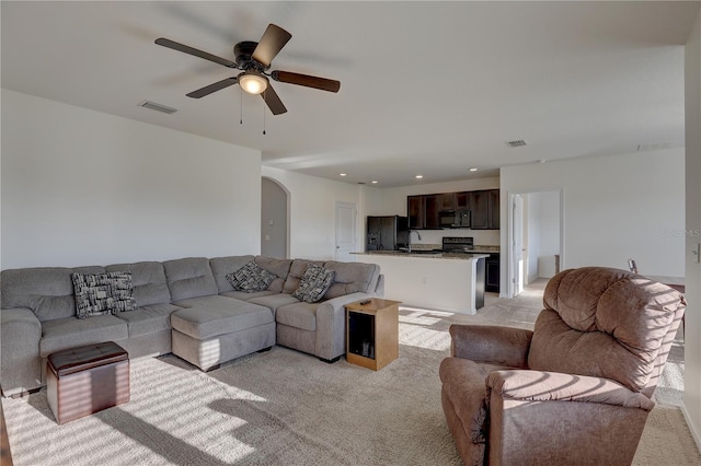 living area featuring light carpet, visible vents, arched walkways, ceiling fan, and recessed lighting