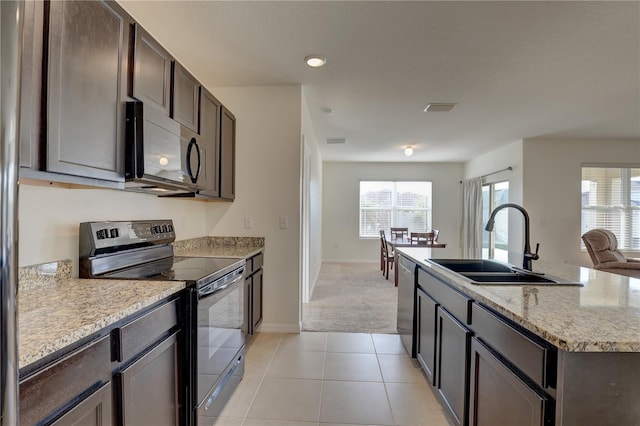 kitchen featuring light tile patterned flooring, a sink, visible vents, black electric range, and dishwasher