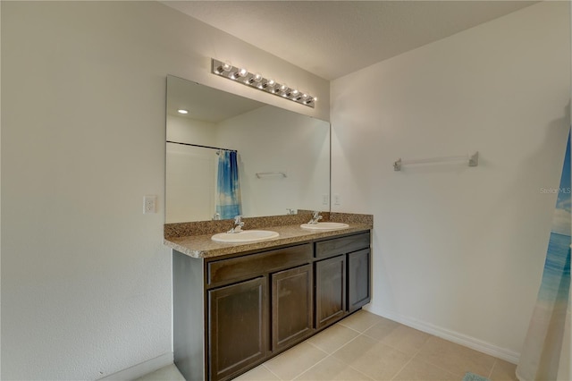 bathroom featuring double vanity, a shower with shower curtain, a sink, and baseboards