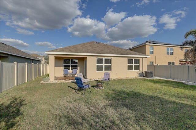 back of house with an outdoor fire pit, a fenced backyard, a lawn, and stucco siding