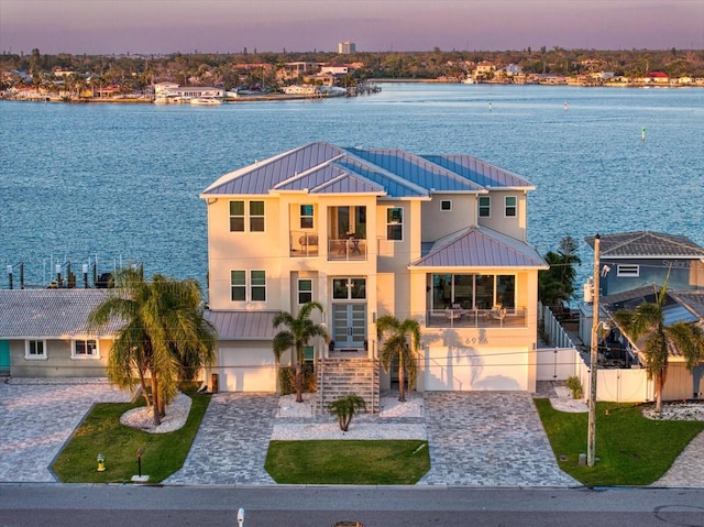 view of front of property featuring decorative driveway, a water view, and a garage